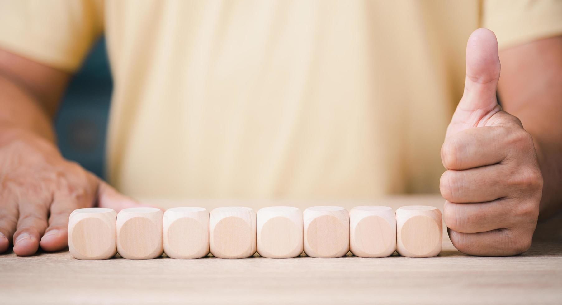 Wooden blocks lined up, businessman showing confidence, structural development thinking and teamwork. photo