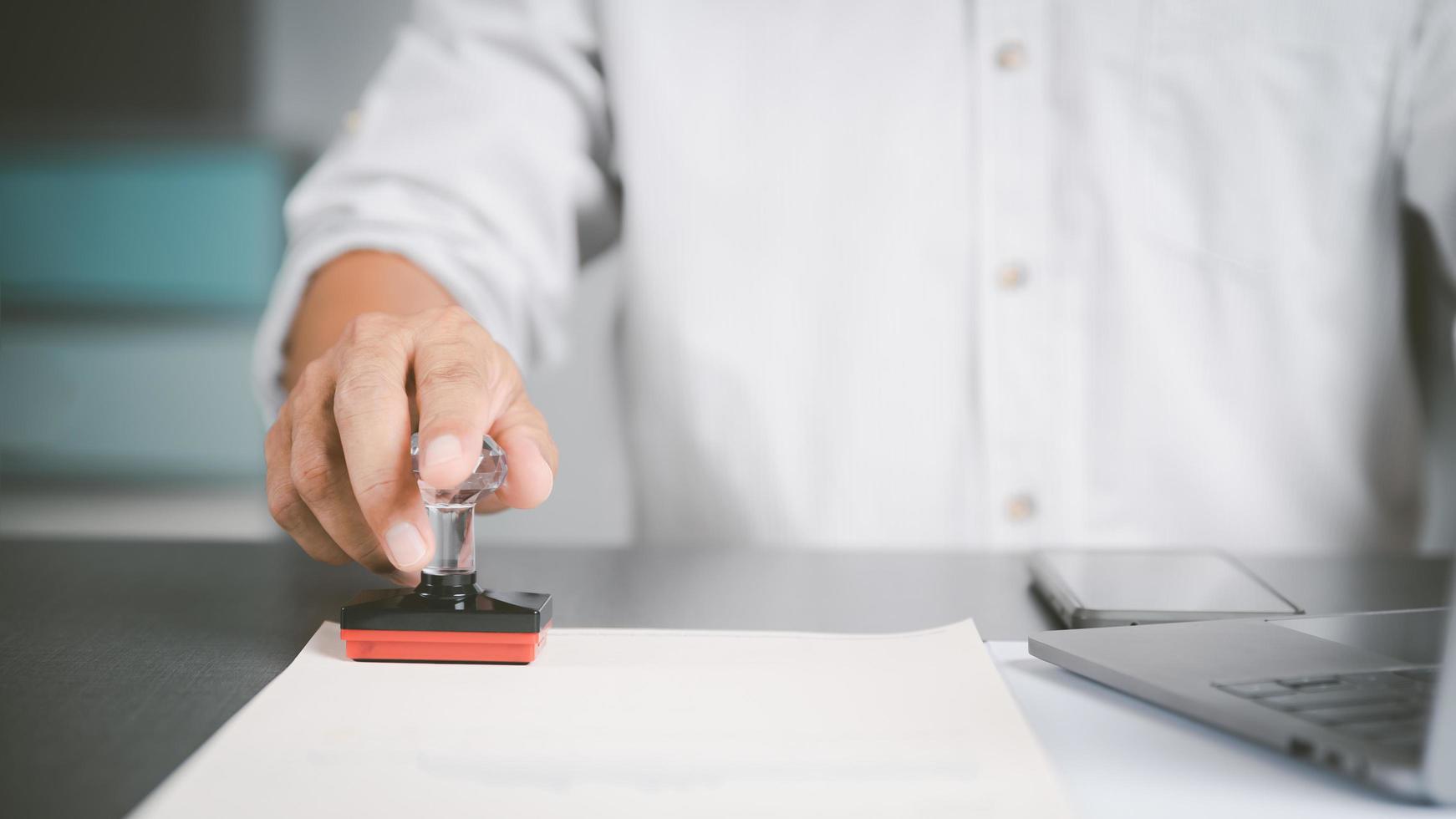 A young executive is stamping on documents for a business contract. Transaction and document management concepts include negotiating corporate entities and filling out legal forms or agreements. photo