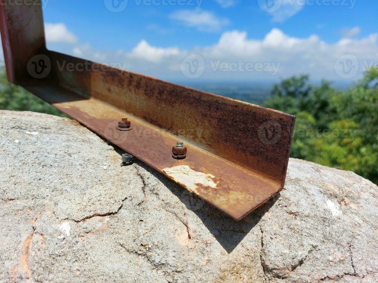 placa de acero oxidado y tornillo oxidado en roca al aire libre. foto