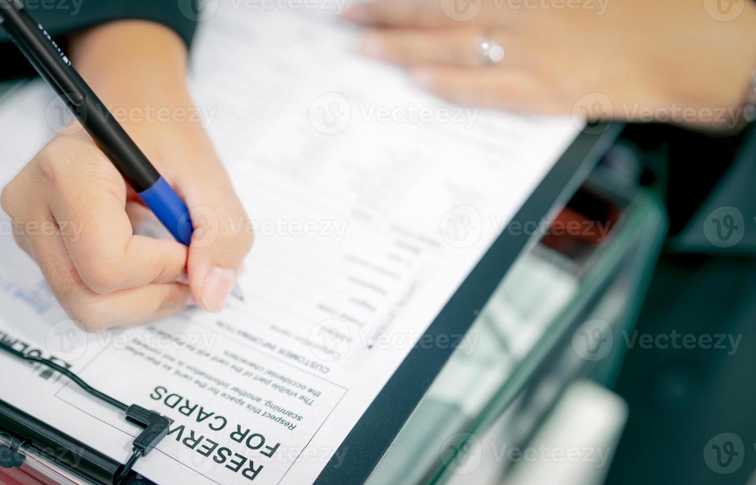 Business people hand holding pen and fill corporation profile in paper form for contract agreement, and complete deal. Document work or paperwork. Contract and agreement document on desk. Deal concept photo