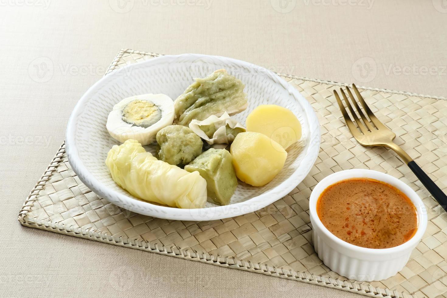 siomay bandung, albóndigas al vapor con huevo cocido, tofu, patatas y rollo de col. Comida callejera tradicional indonesia con salsa de cacahuete y salsa de soja, servida con lima verde. foto