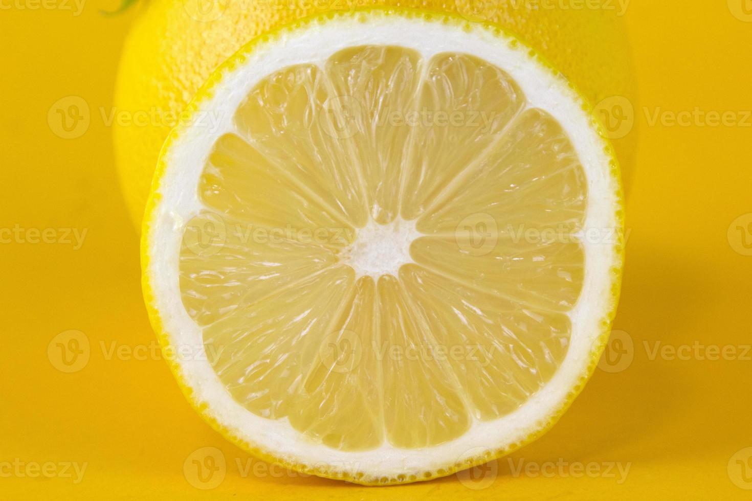 Close up view of textured ripe slice of lemon citrus fruit isolated on yellow background. Lemon slice with clipping path for healthy food concept design photo