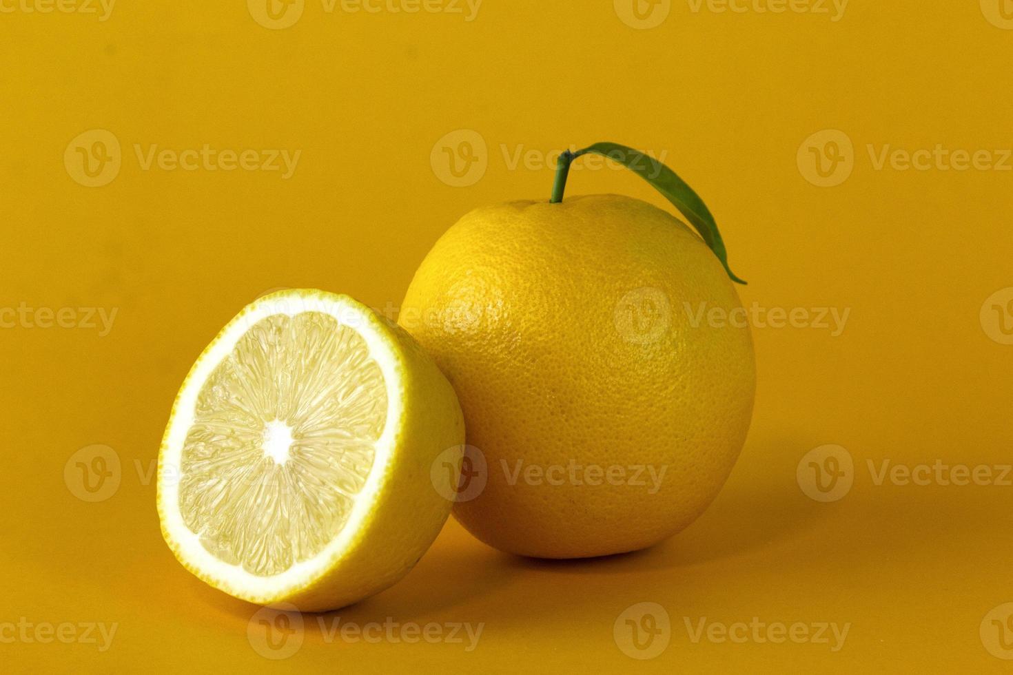 Organic lemon fruits and a Lemon slice with leaf isolated on yellow background photo