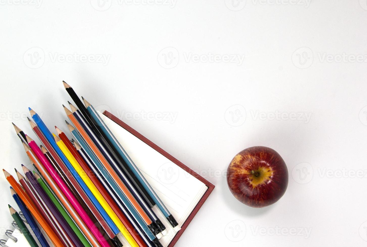 concepto de regreso a la escuela con materiales educativos, cuaderno, manzana, bolígrafo aislado en fondo blanco. plantilla de conceptos de vista superior para carteles foto