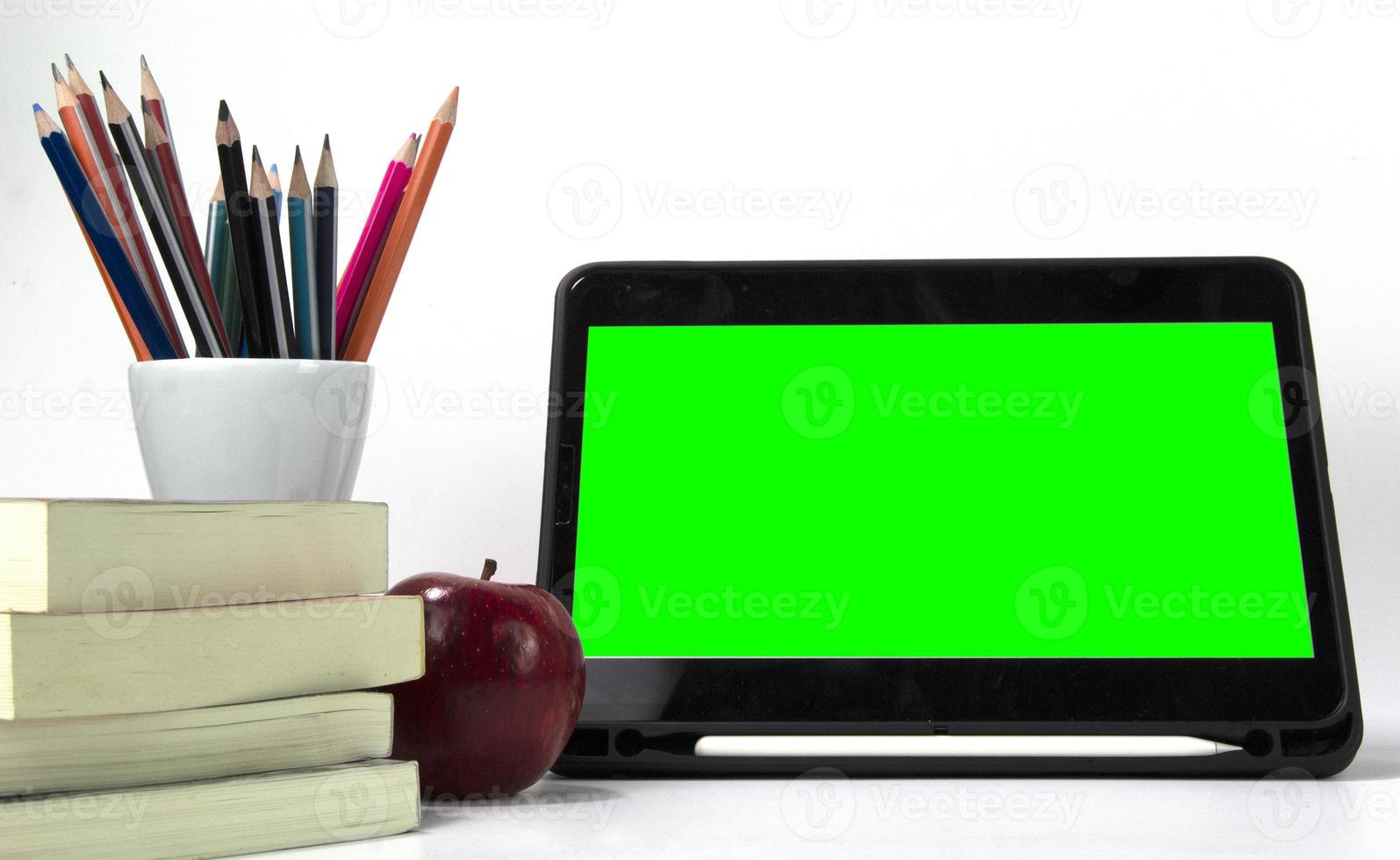 materiales educativos en la caja, con pantalla verde ipad y libros aislados en fondo blanco. diseño de concepto de póster de regreso a la escuela foto