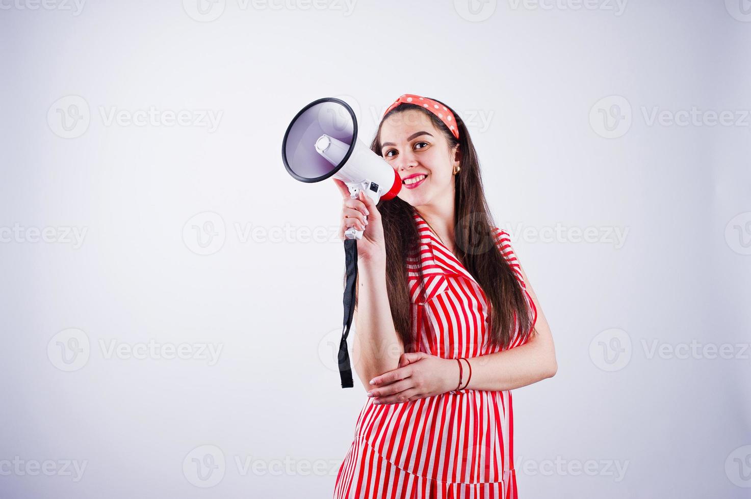 Portrait of a young beautiful woman in red dress talking into megaphone. photo