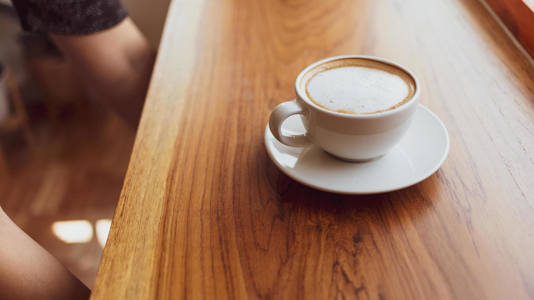 Cup of cappuccino coffee with a latte on a wooden bar in a sunlit cafe in the morning. photo