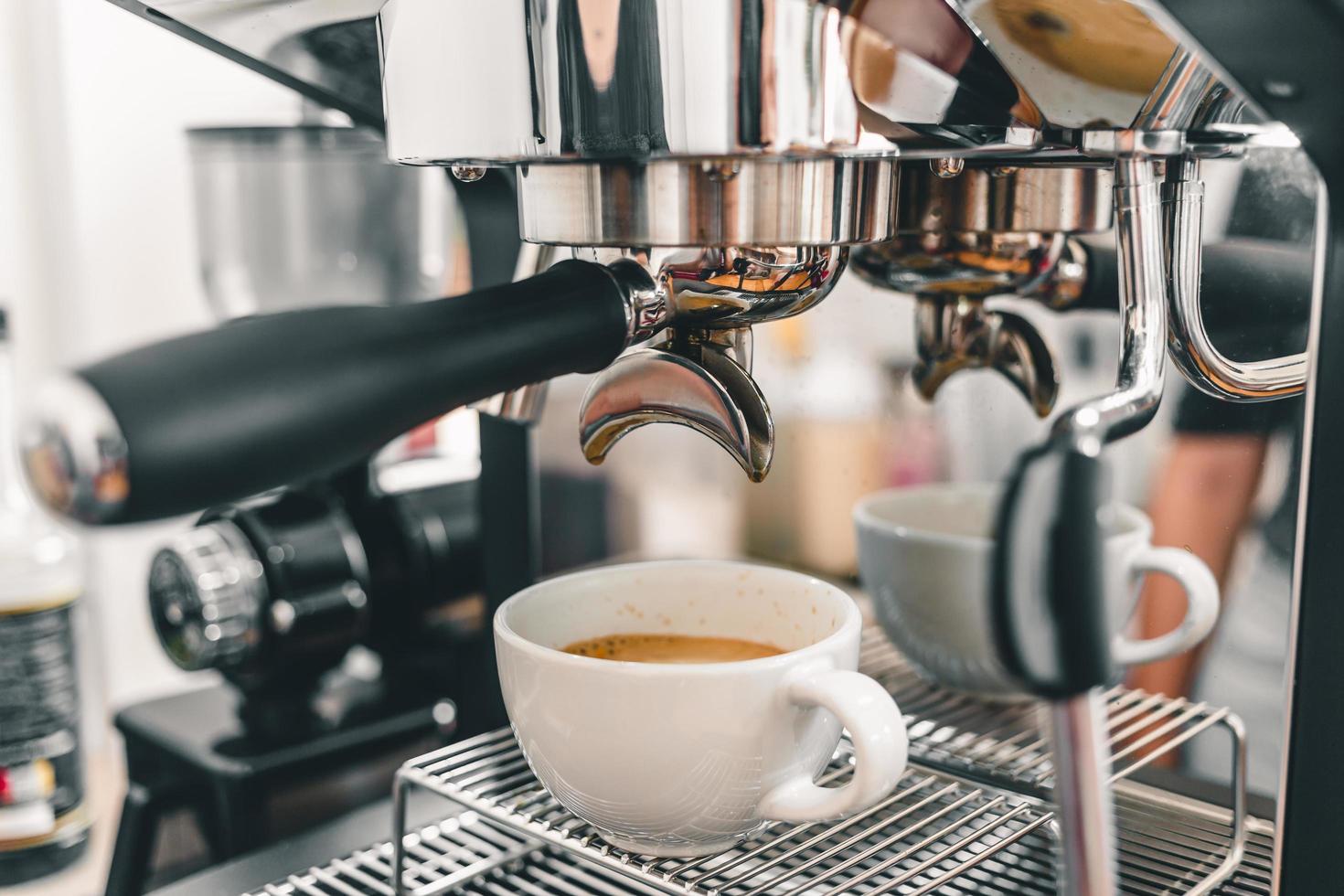 extracción de café de la máquina de café barista profesional. espresso que se vierte de una máquina de café en una taza de café en una cafetería. foto