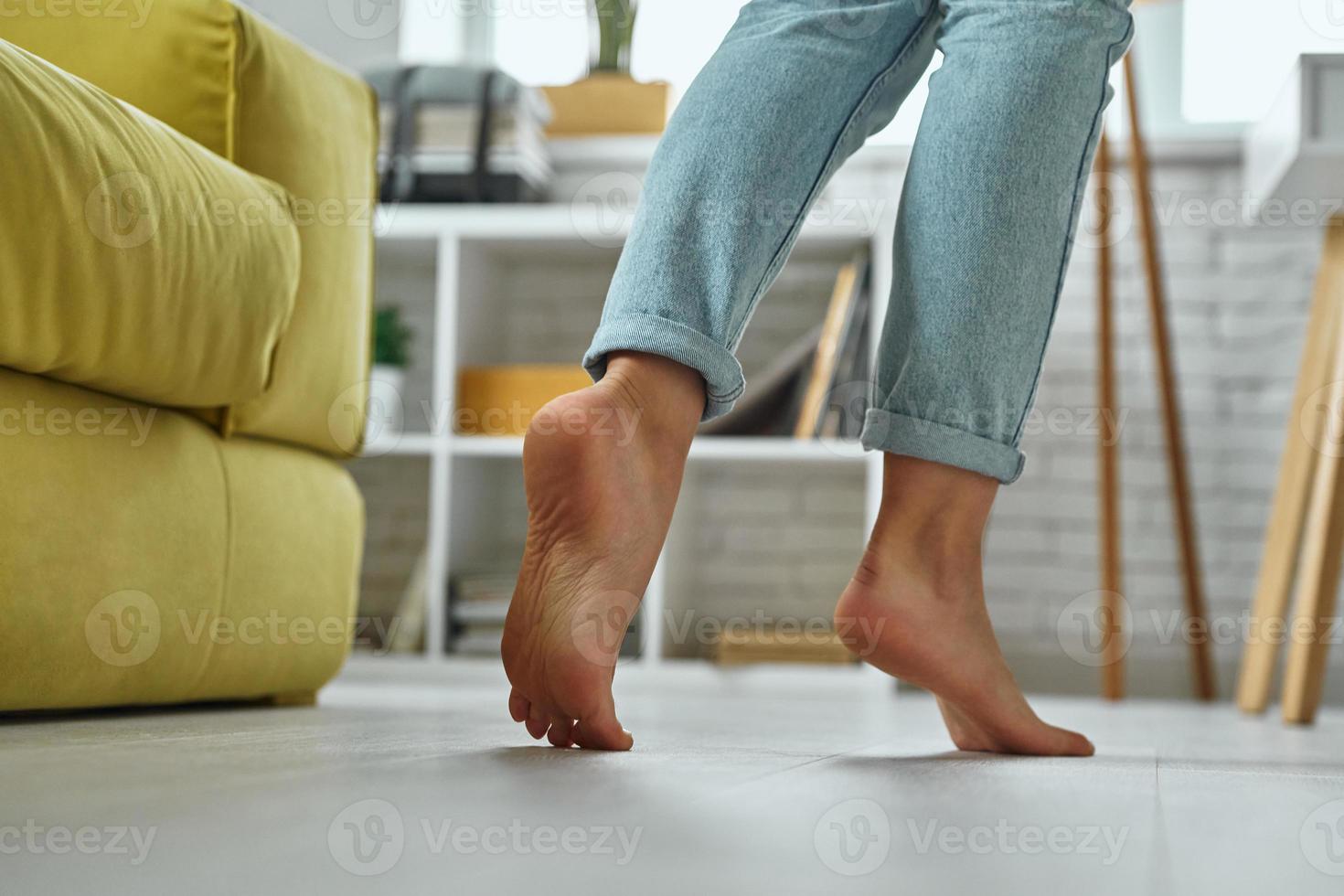 Close-up of barefoot woman walking on wooden floor at home photo