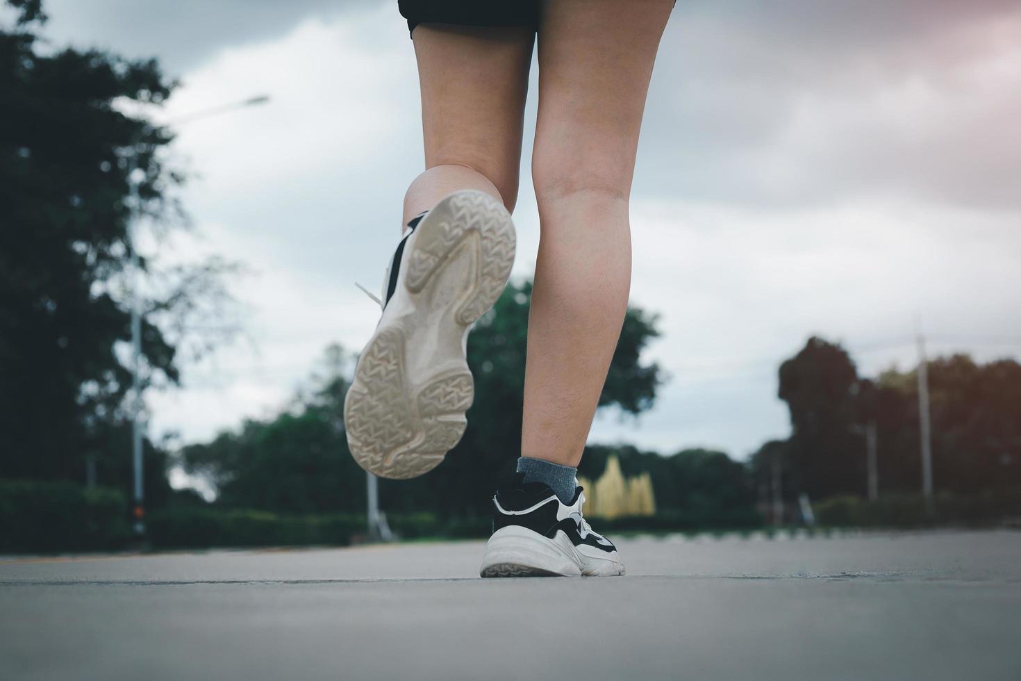 Close up of young  woman shoes walking outdoors in running shoes from behind. photo