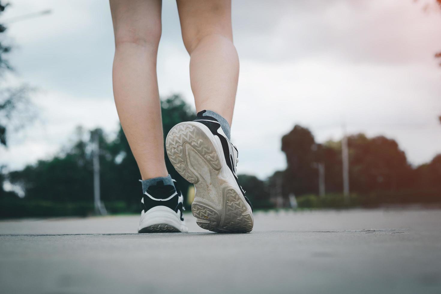 Close up of young  woman shoes walking outdoors in running shoes from behind. photo