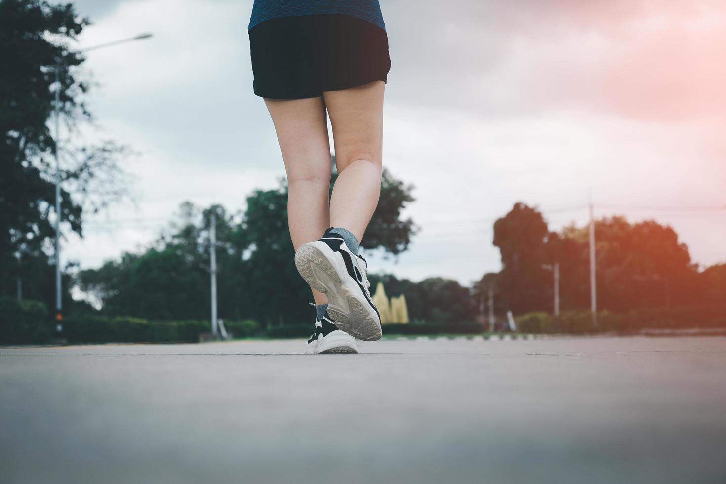 Close up of young woman shoes walking outdoors in running shoes from behind. photo