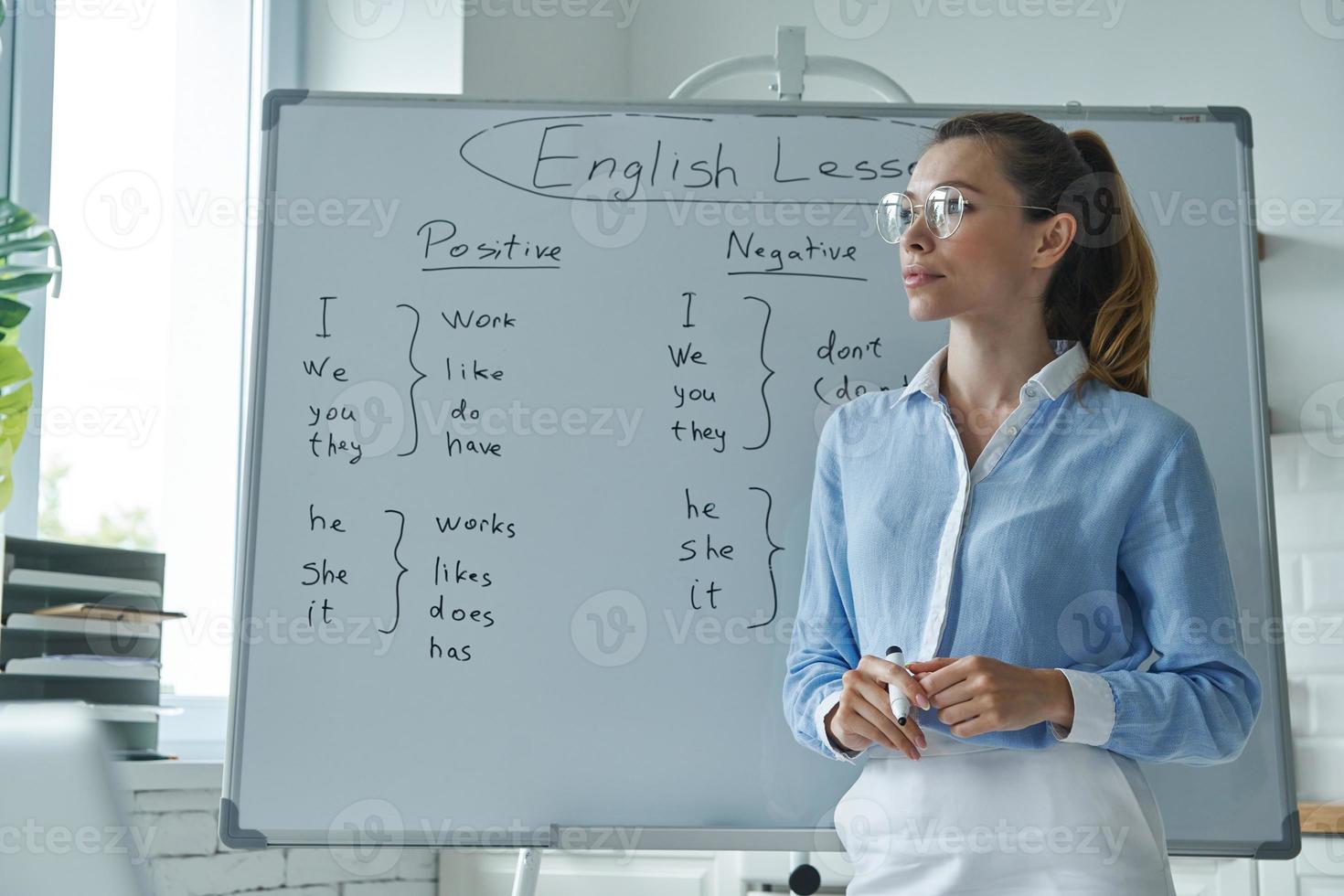Thoughtful young woman standing near the whiteboard at the classroom photo