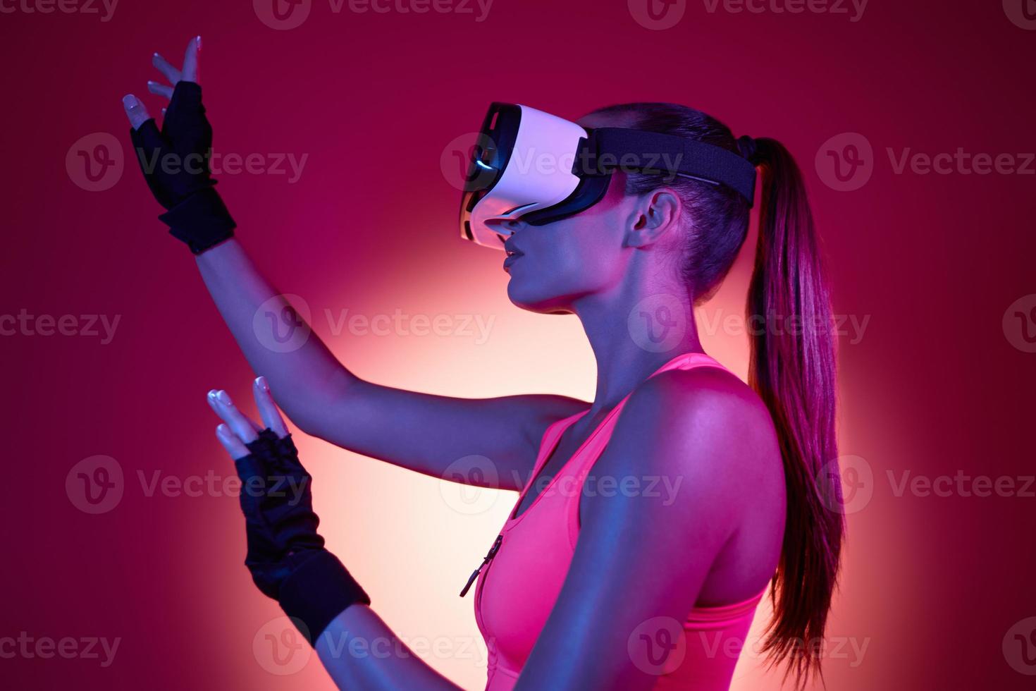 Young woman in virtual reality glasses gesturing against colorful background photo