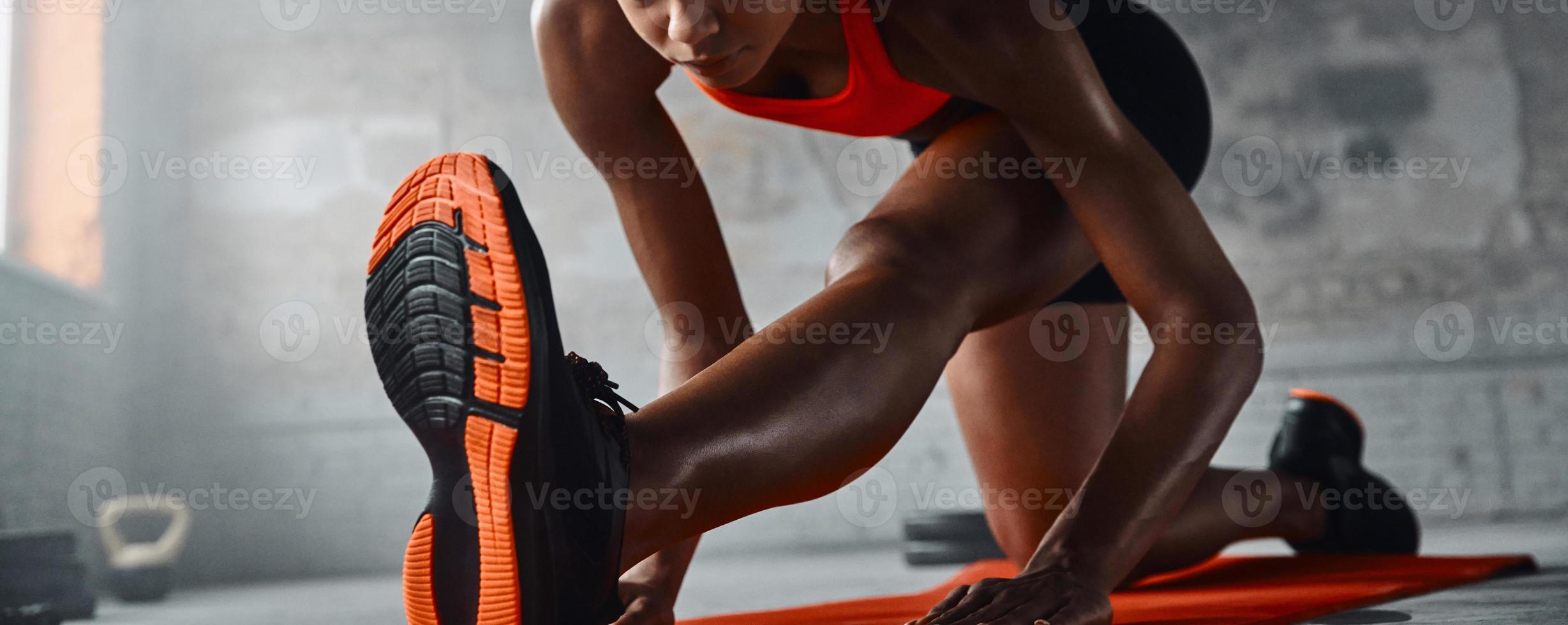 Close-up of young African woman doing stretching exercises in gym photo