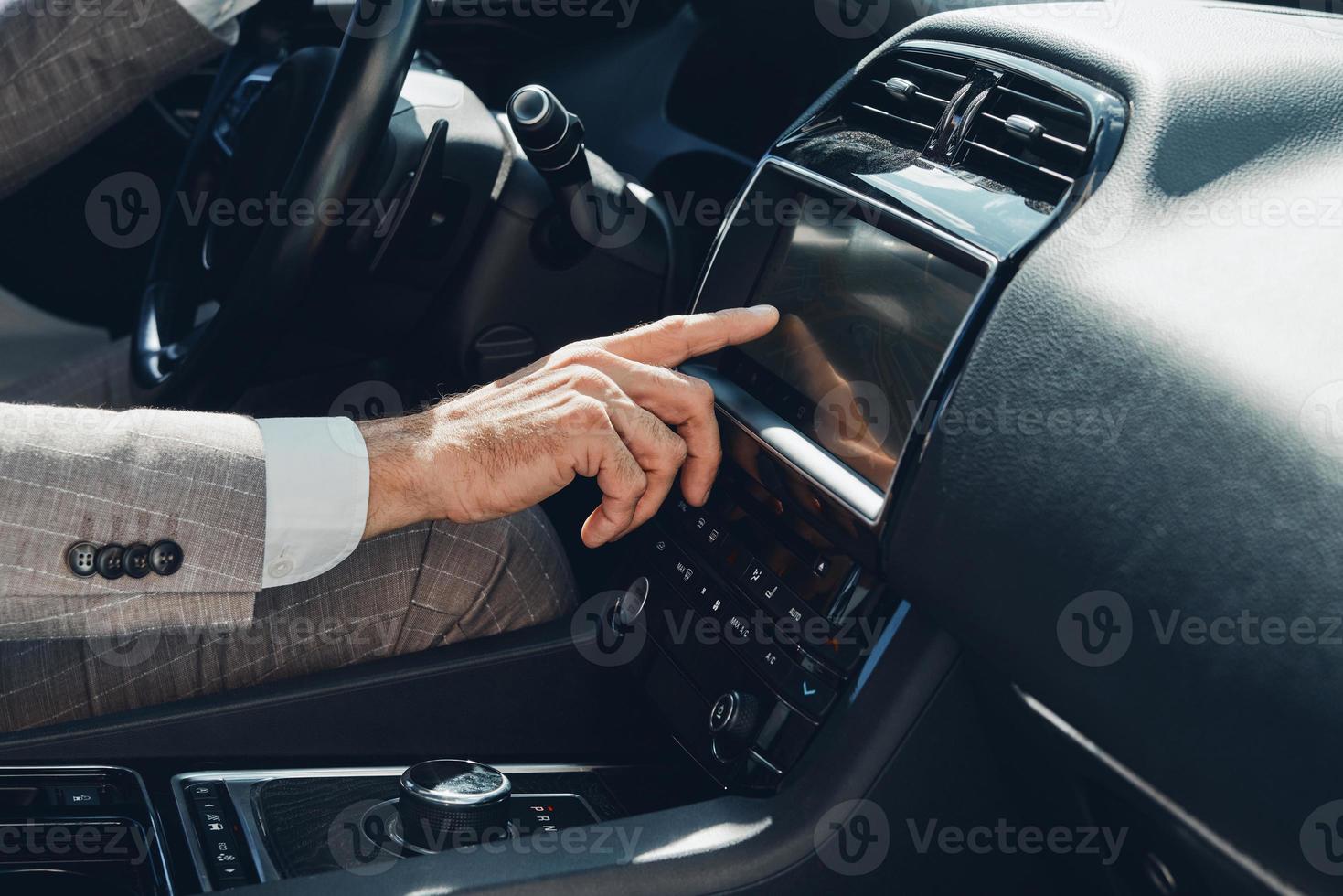 Close-up of man using control panel while sitting on the front seat of a car photo