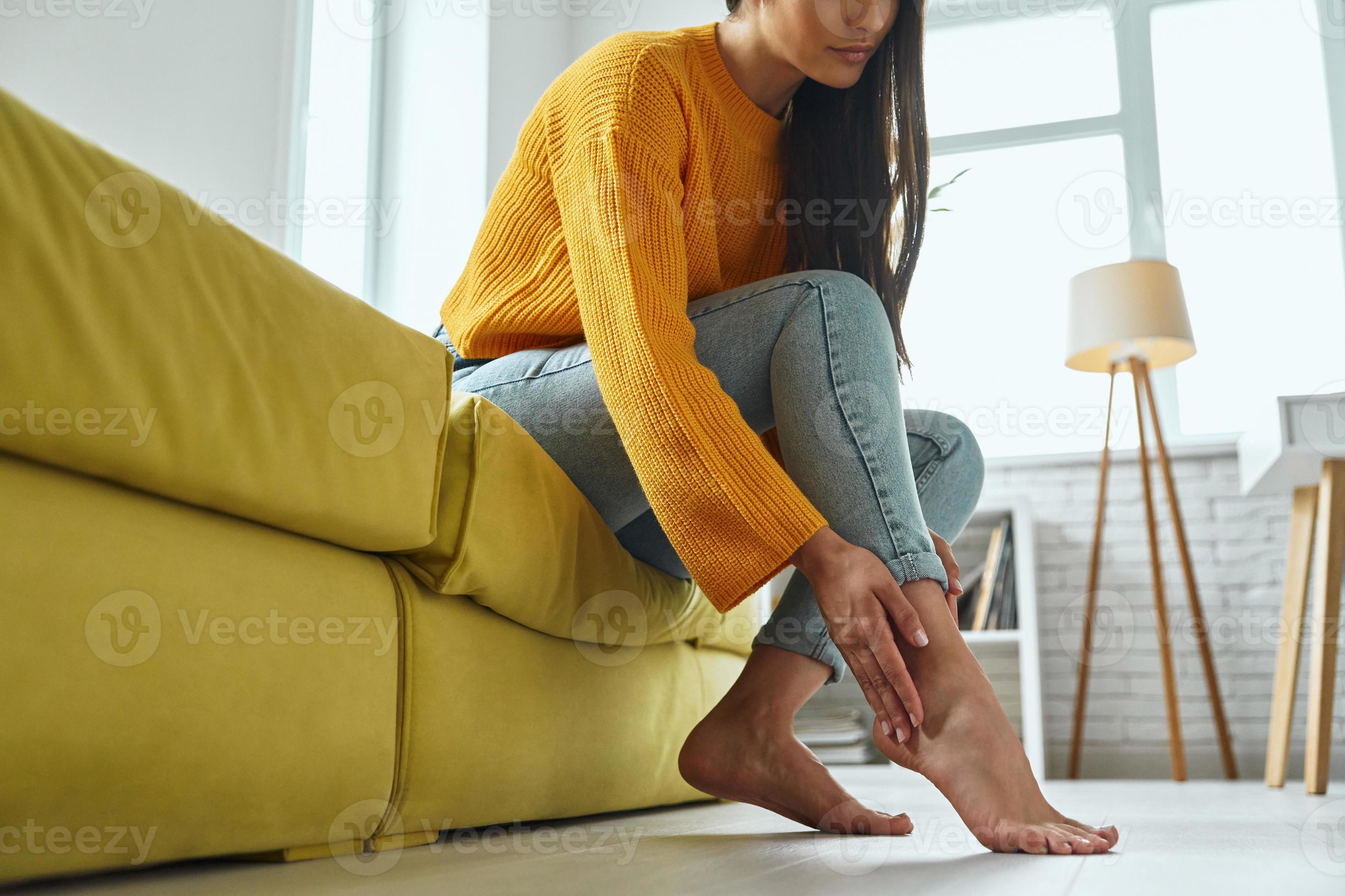 Closeup of young woman massaging her tired feet while sitting on the