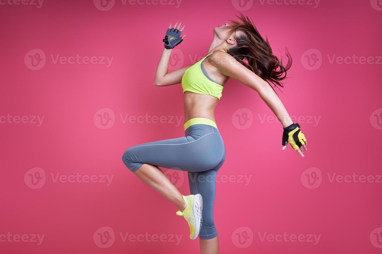 mujer joven confiada en ropa deportiva haciendo ejercicio contra fondo rosa foto