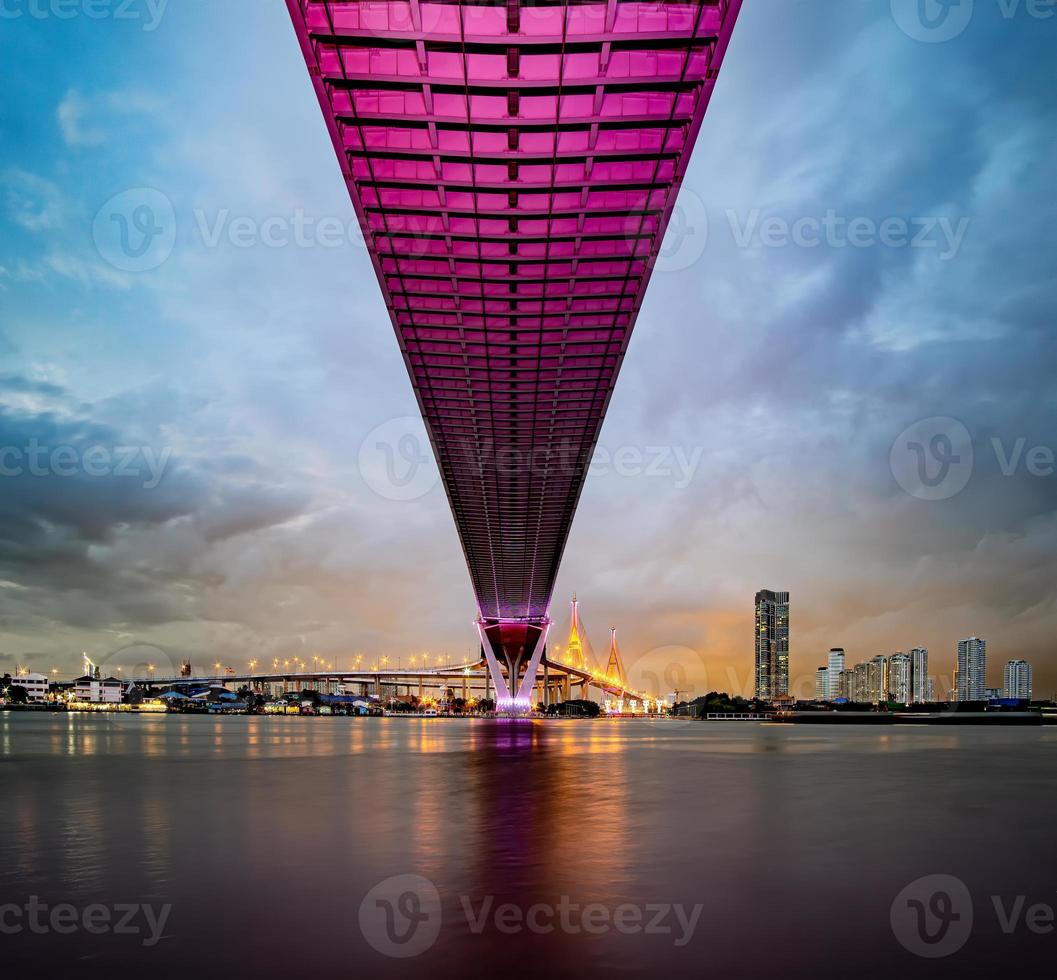 Purple led light under the bridge over the river On a cloudy day in the sky. Bhumibol Bridge, Samut Prakan, Thailand photo