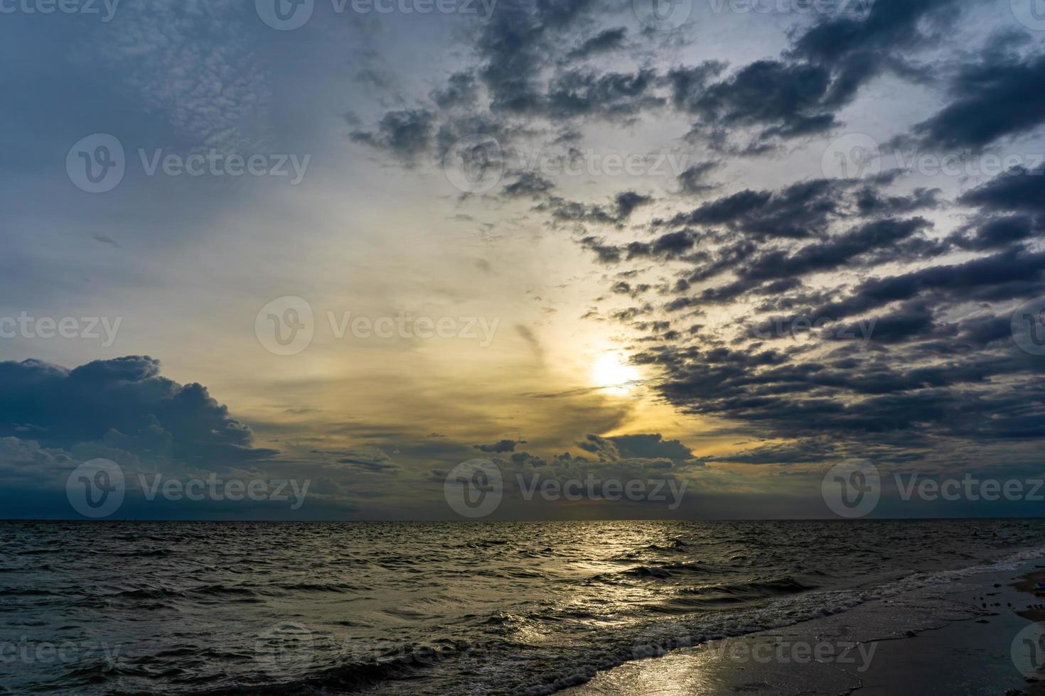 el cielo de la tarde tiene nubes llenas de cielo, la luz del sol refleja el agua de mar, la superficie del mar foto