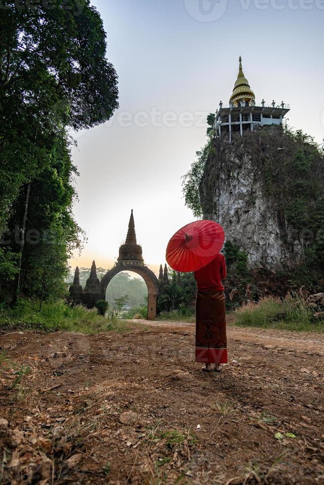 mujeres con trajes nacionales tailandeses con el paraguas rojo parado frente a la puerta principal, el tiempo de espera, la imagen pasada, la traducción de la puerta del tiempo en la puerta es el nombre putthawadee foto