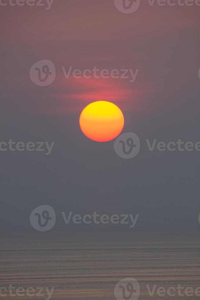 el sol está cayendo en el mar. , el cielo es naranja y el mar es oscuro foto