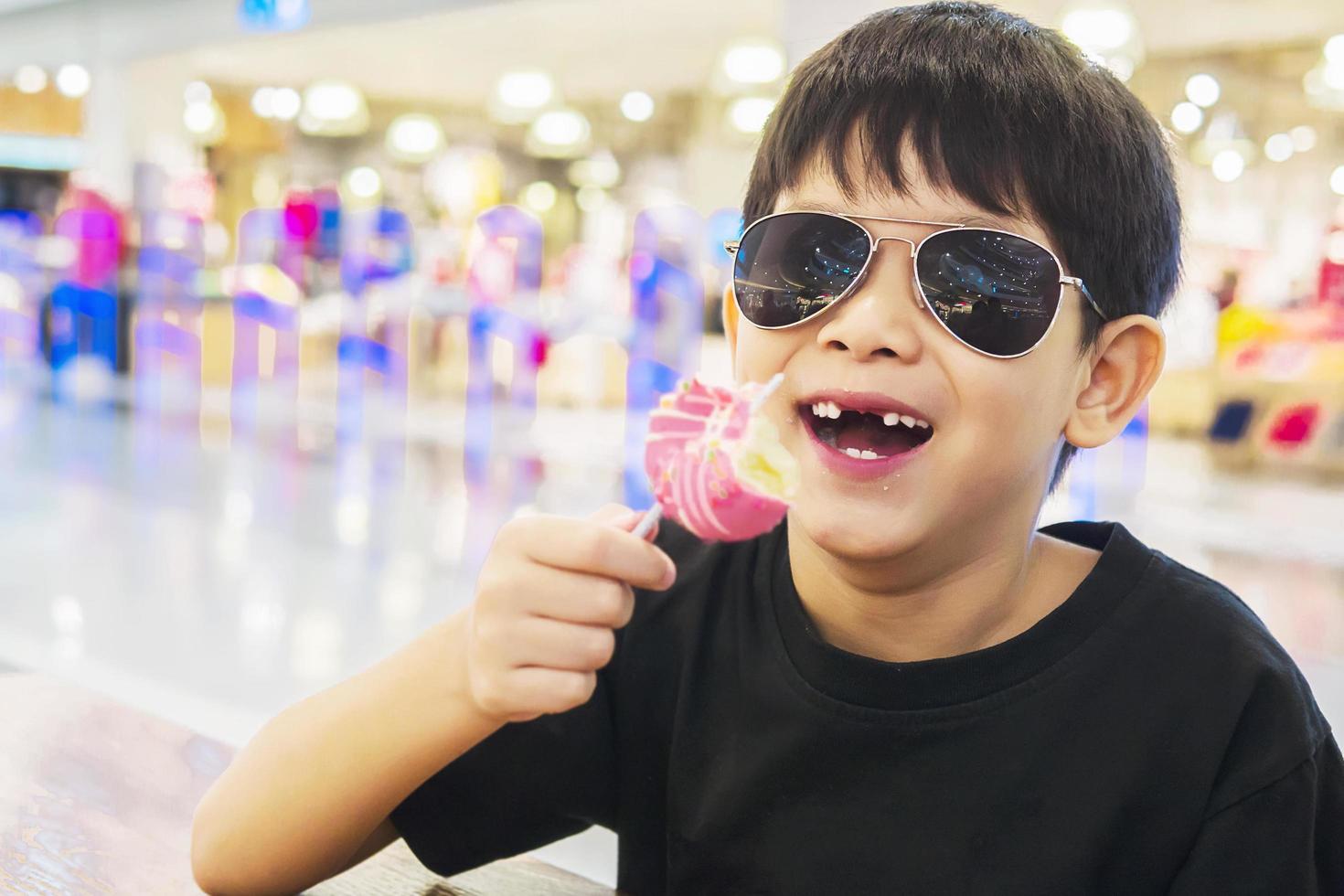 Kid with broken teeth is eating donuts happily photo