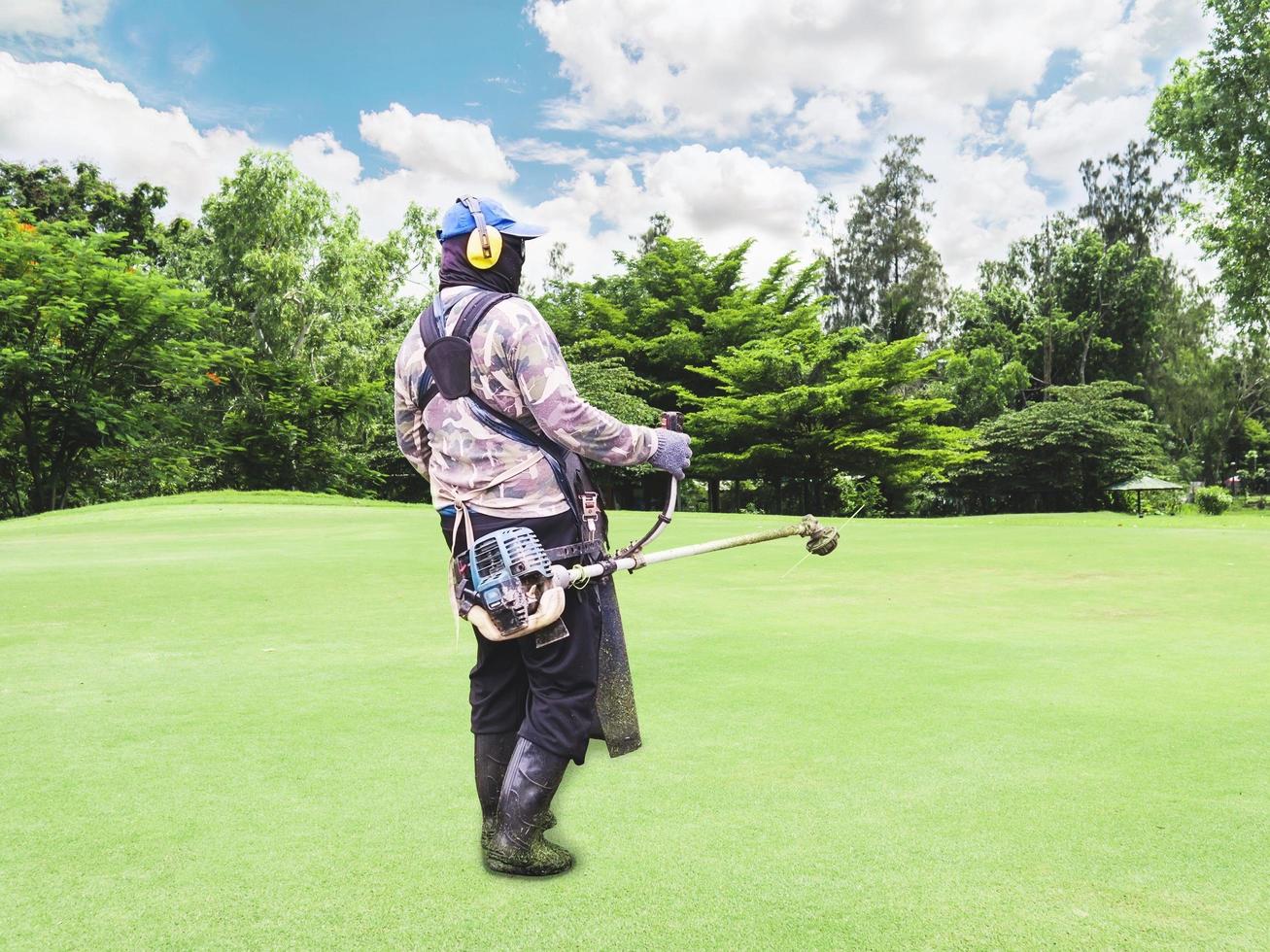 Work man using grass cutter machine on green grass field photo