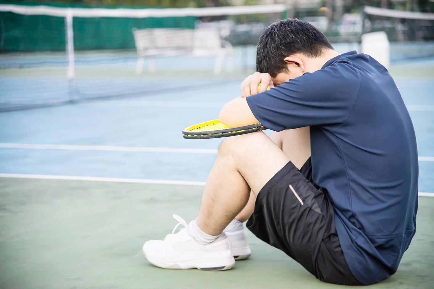 Sad tennis player sitting in the court after lose a match - people in sport tennis game concept photo