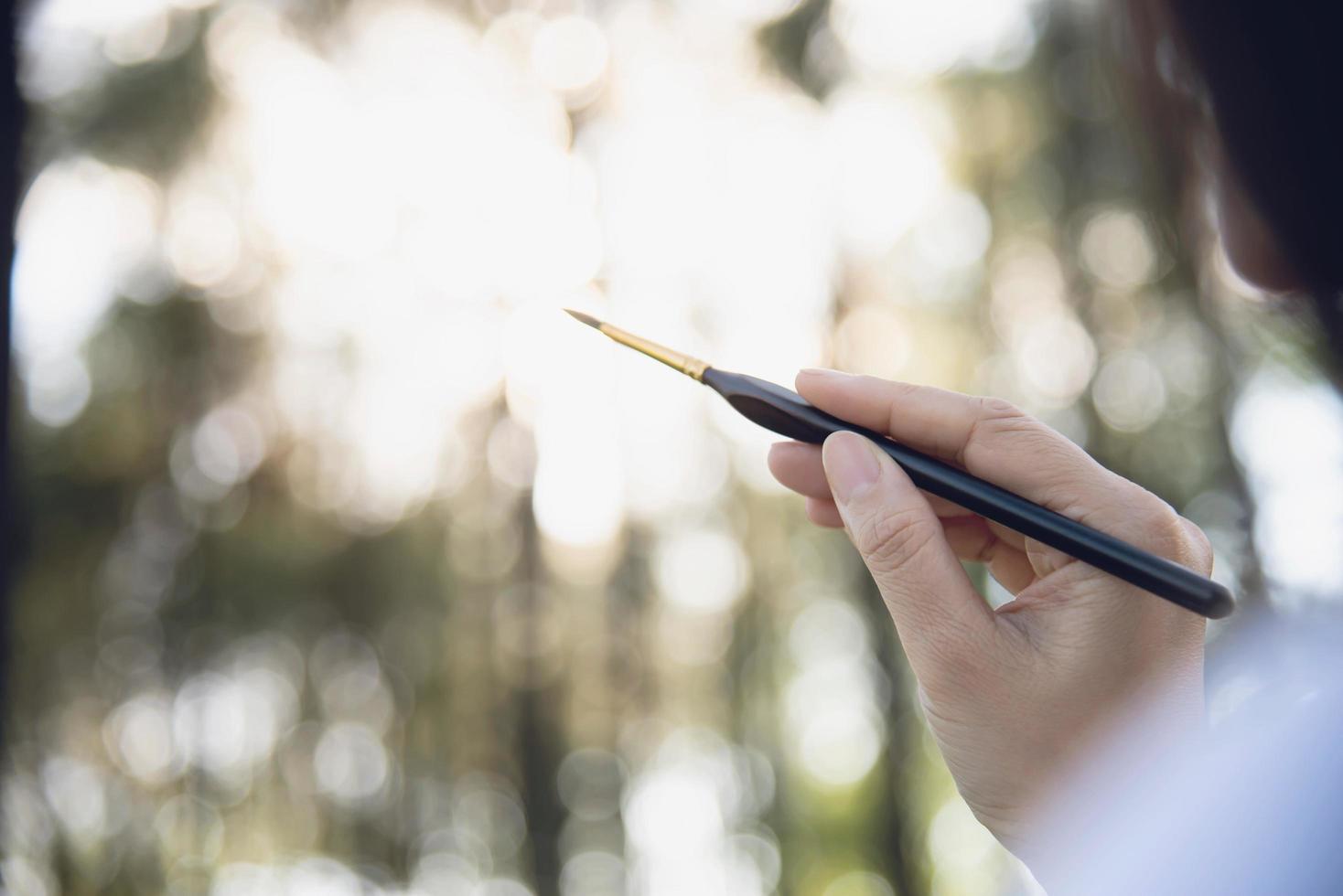 Relax woman painting water colour art work in green garden forest nature - people with creative art in nature stress reduction and meditation concept photo