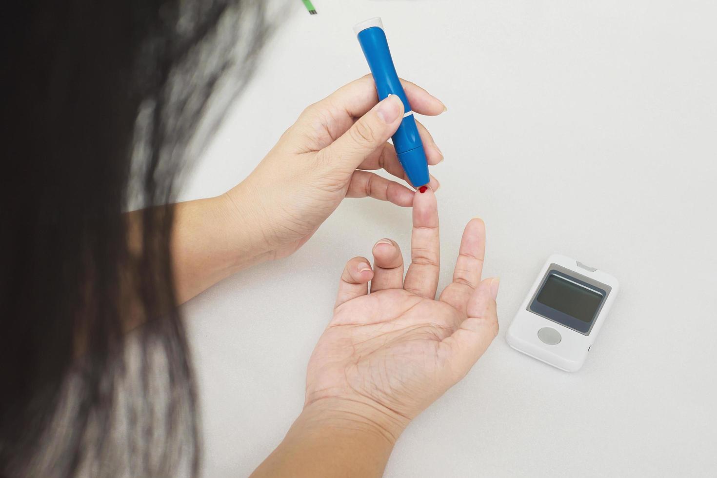 la mujer está controlando la diabetes usando un kit de análisis de sangre foto