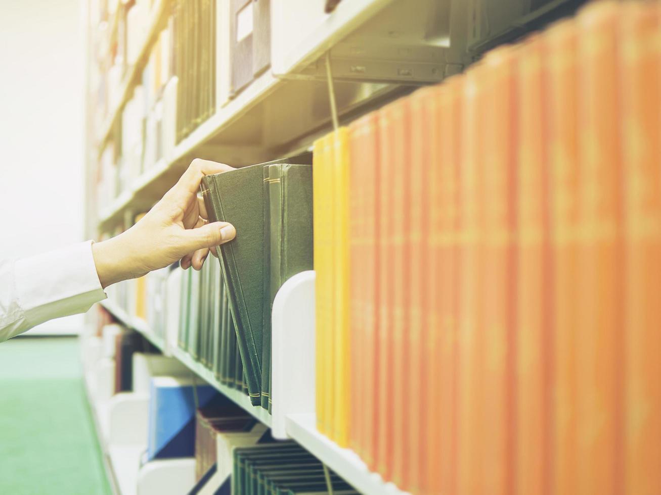 Man is selecting the book from bookshelf in a library photo