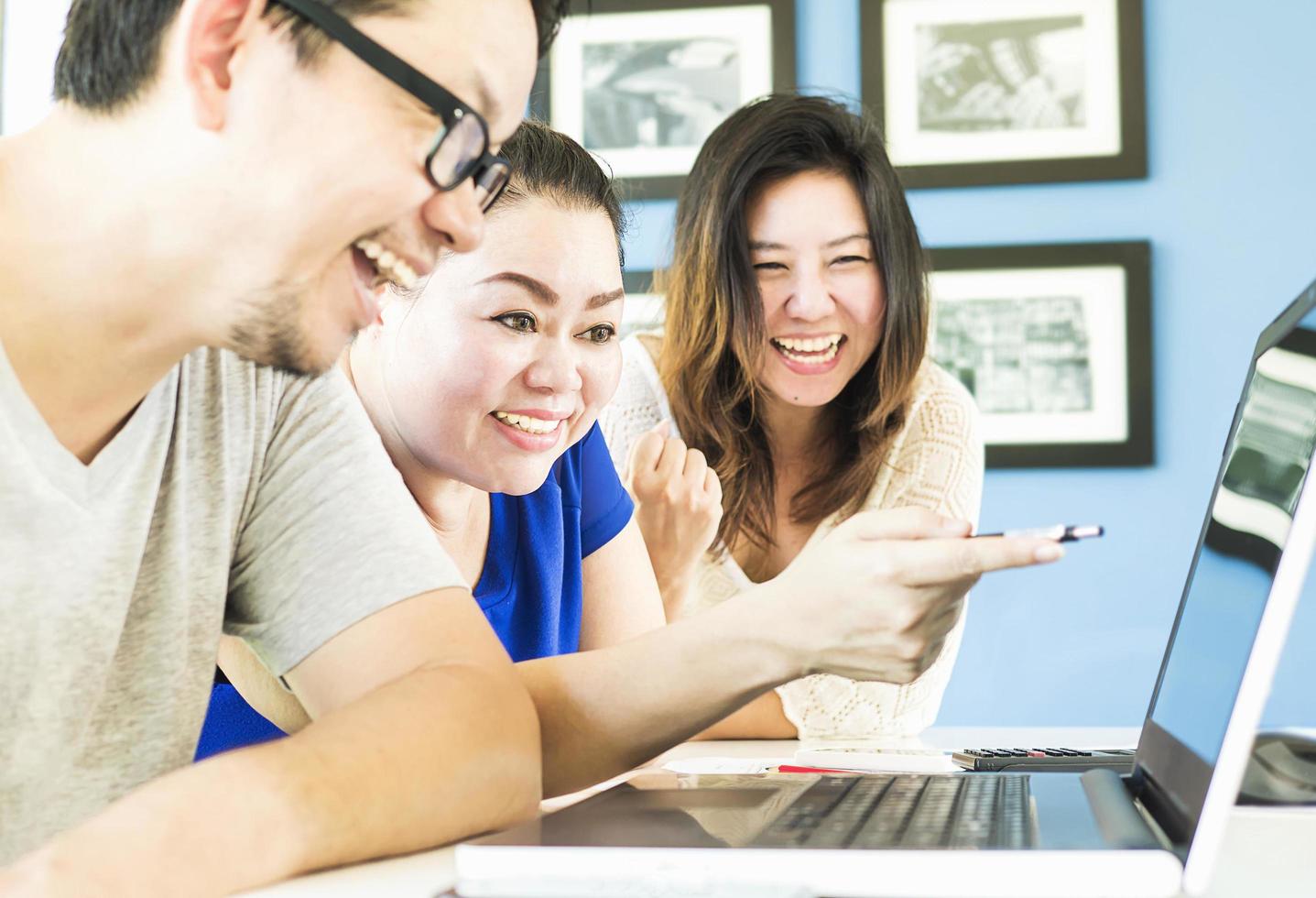 Two women and one man are happily looking at computer in modern office photo