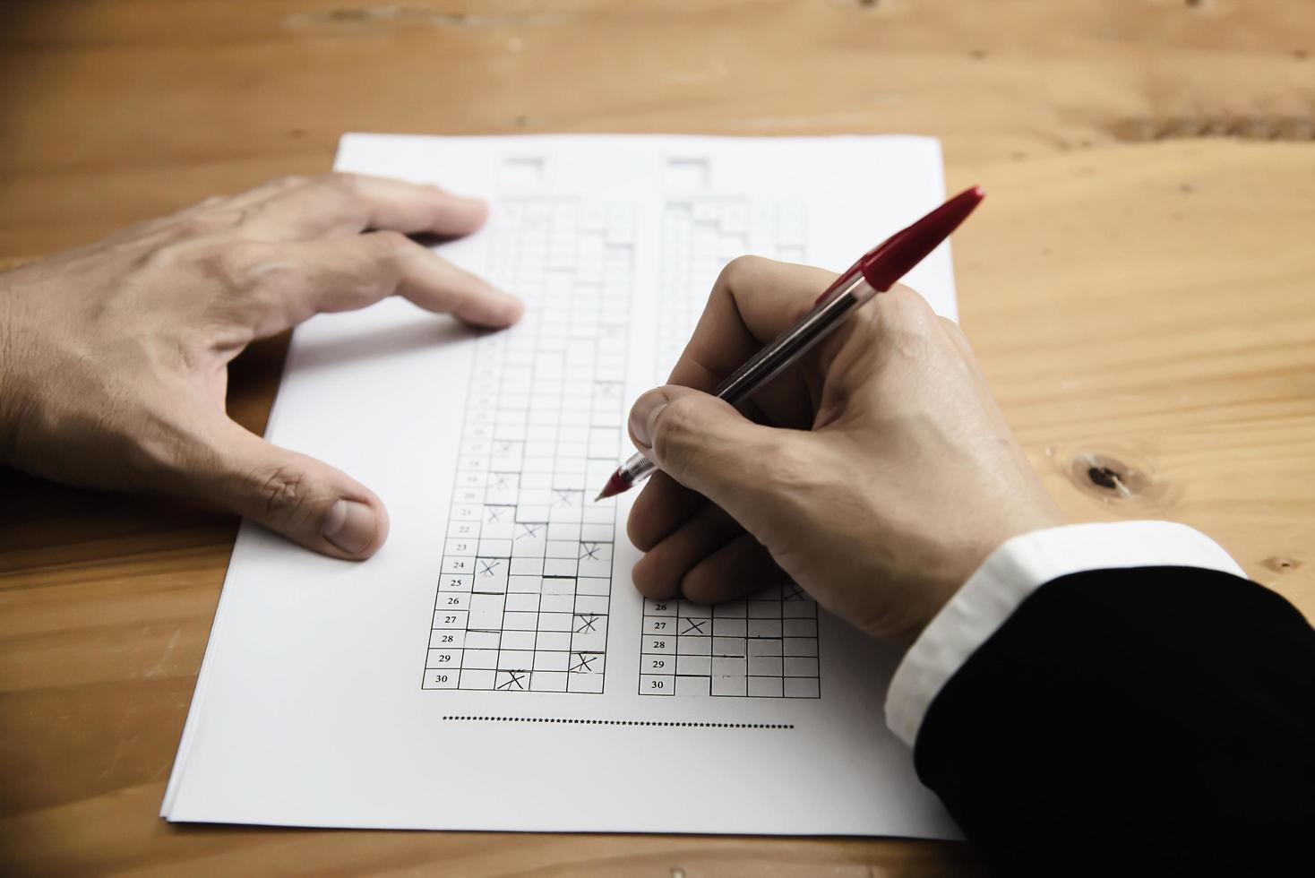 Instructor checking multiple choices answer sheet exam - education people working with paper test concept photo