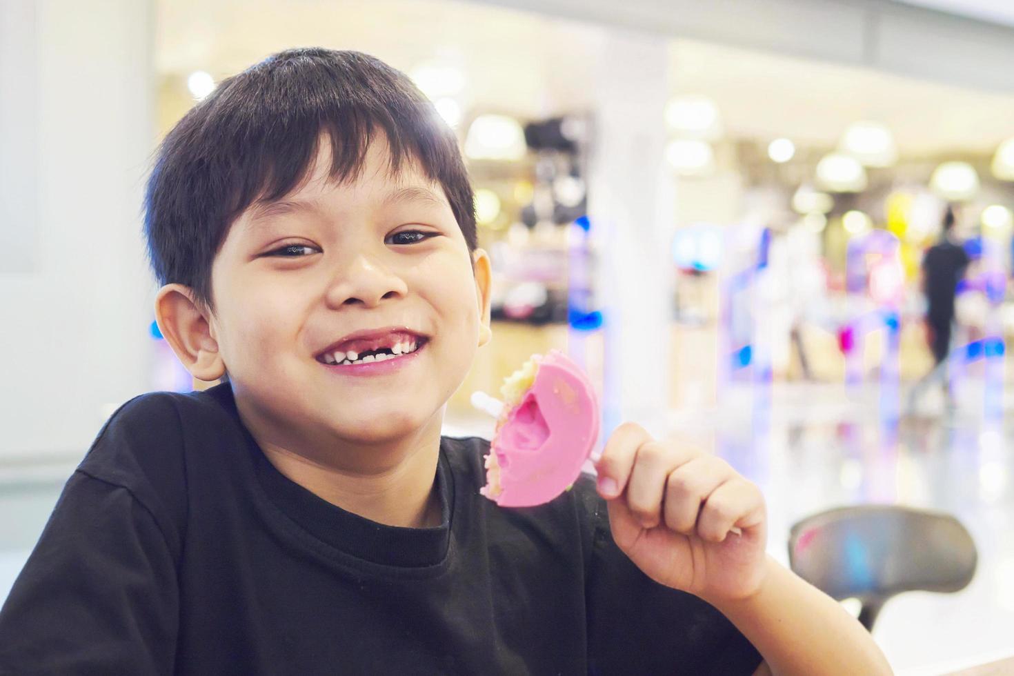 Kid with broken teeth is eating donuts happily photo