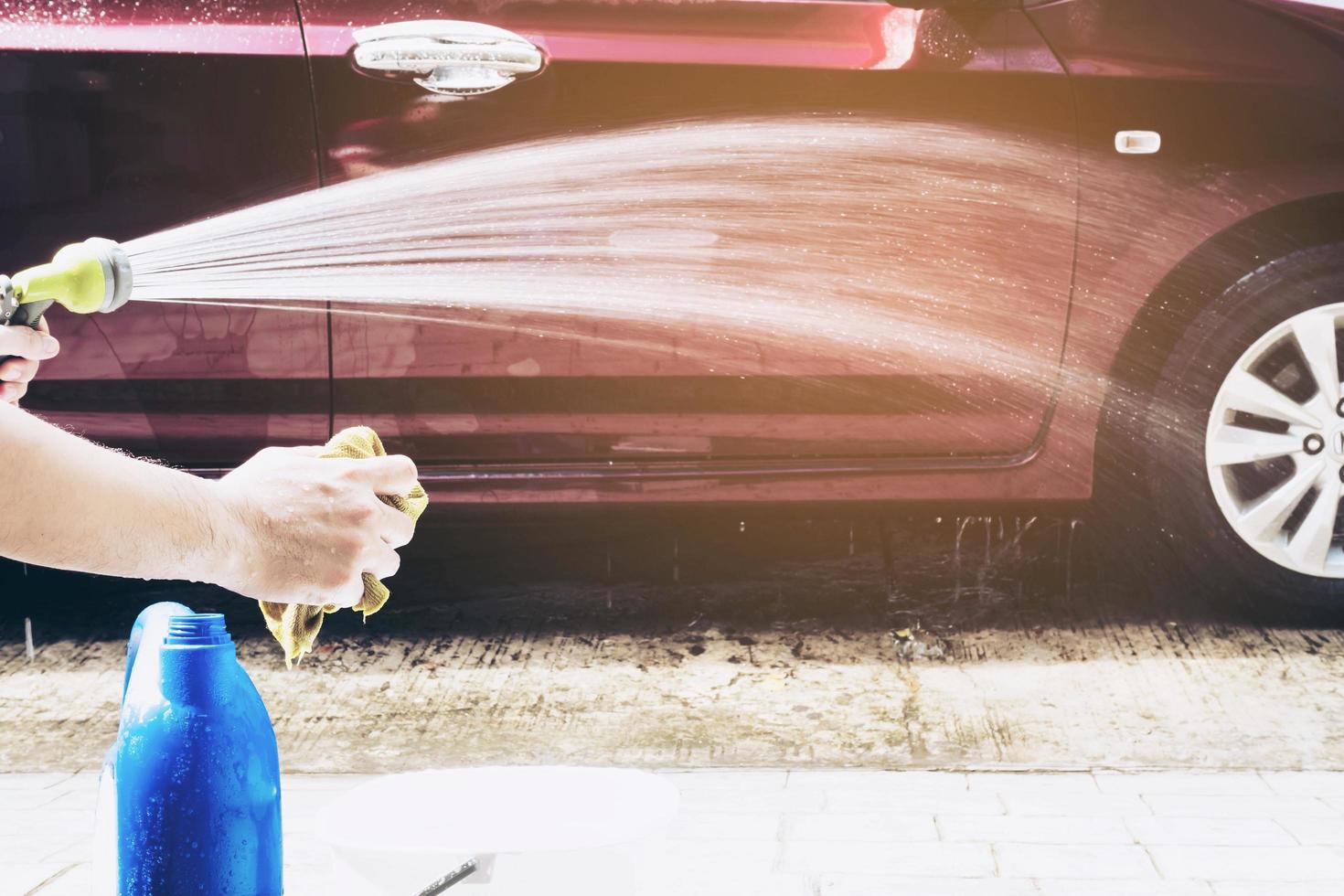 el hombre prepara agua con champú para lavar el auto usando - concepto de limpieza de autos para la gente del hogar foto