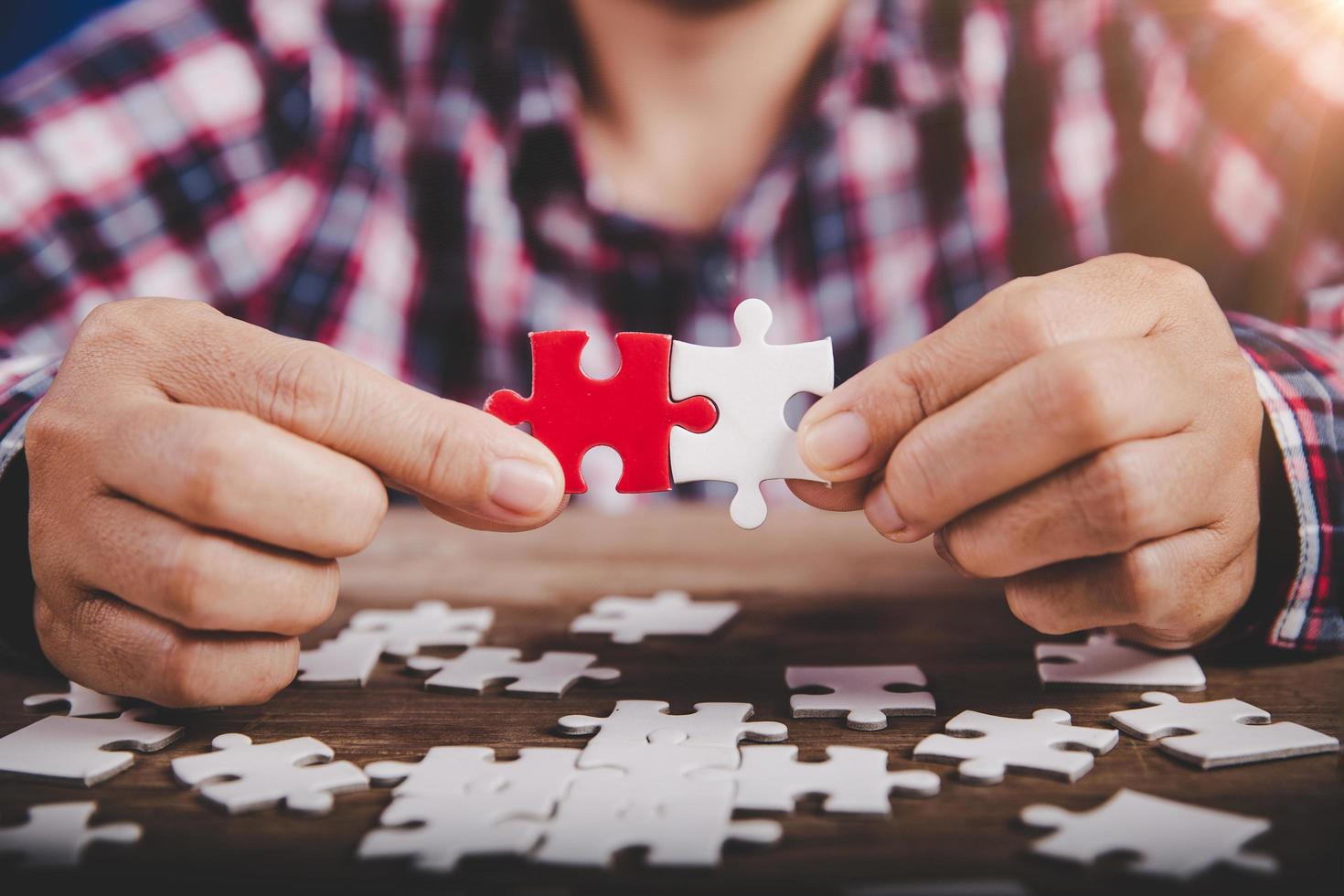 Hands holding jigsaw puzzles piece on wooden table background, success business, solution strategy, teamwork partnership concept photo