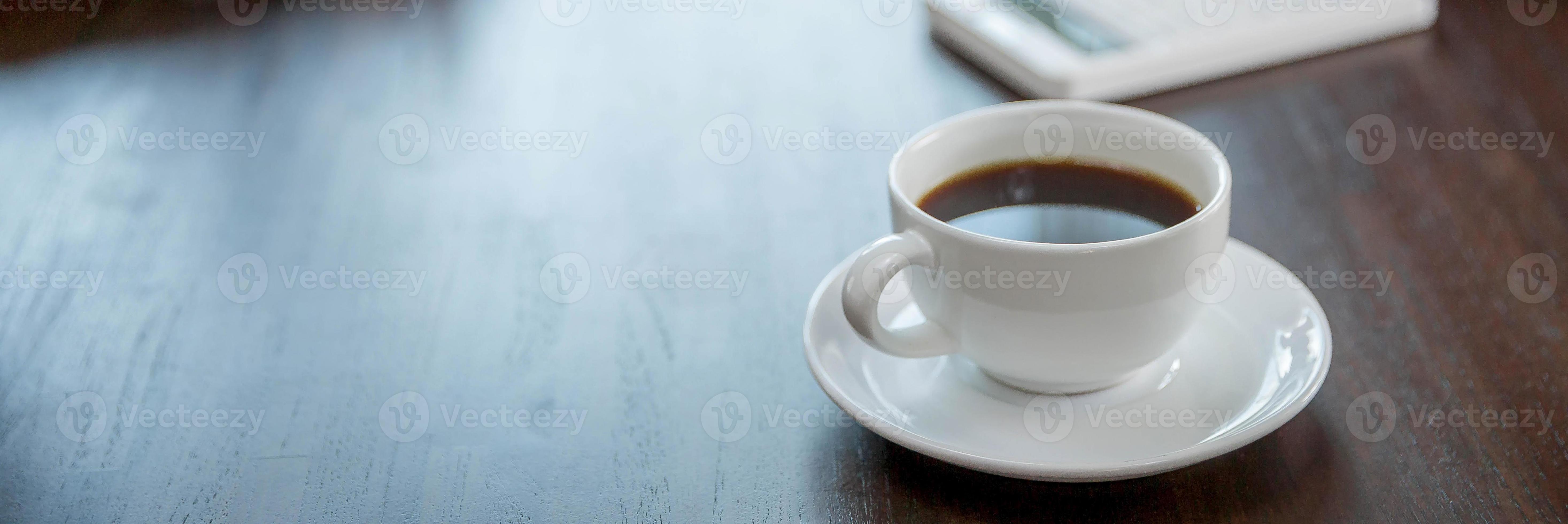 Close up white coffee cup on business black wood table near window in