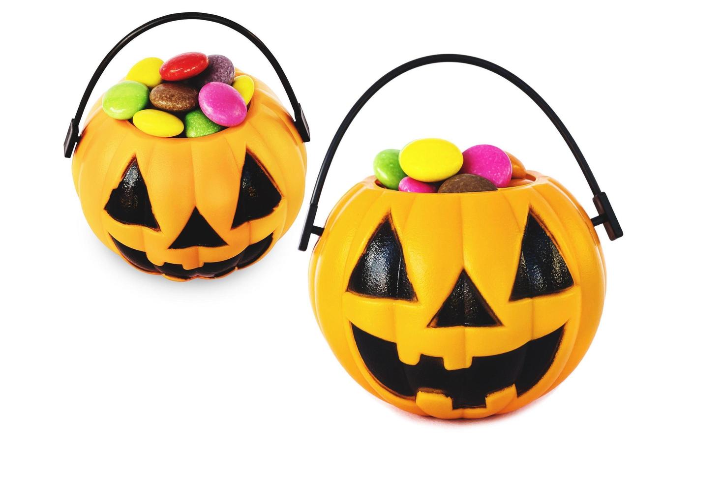 Halloween pumpkin face bucket with colorful candy inside isolated over white photo