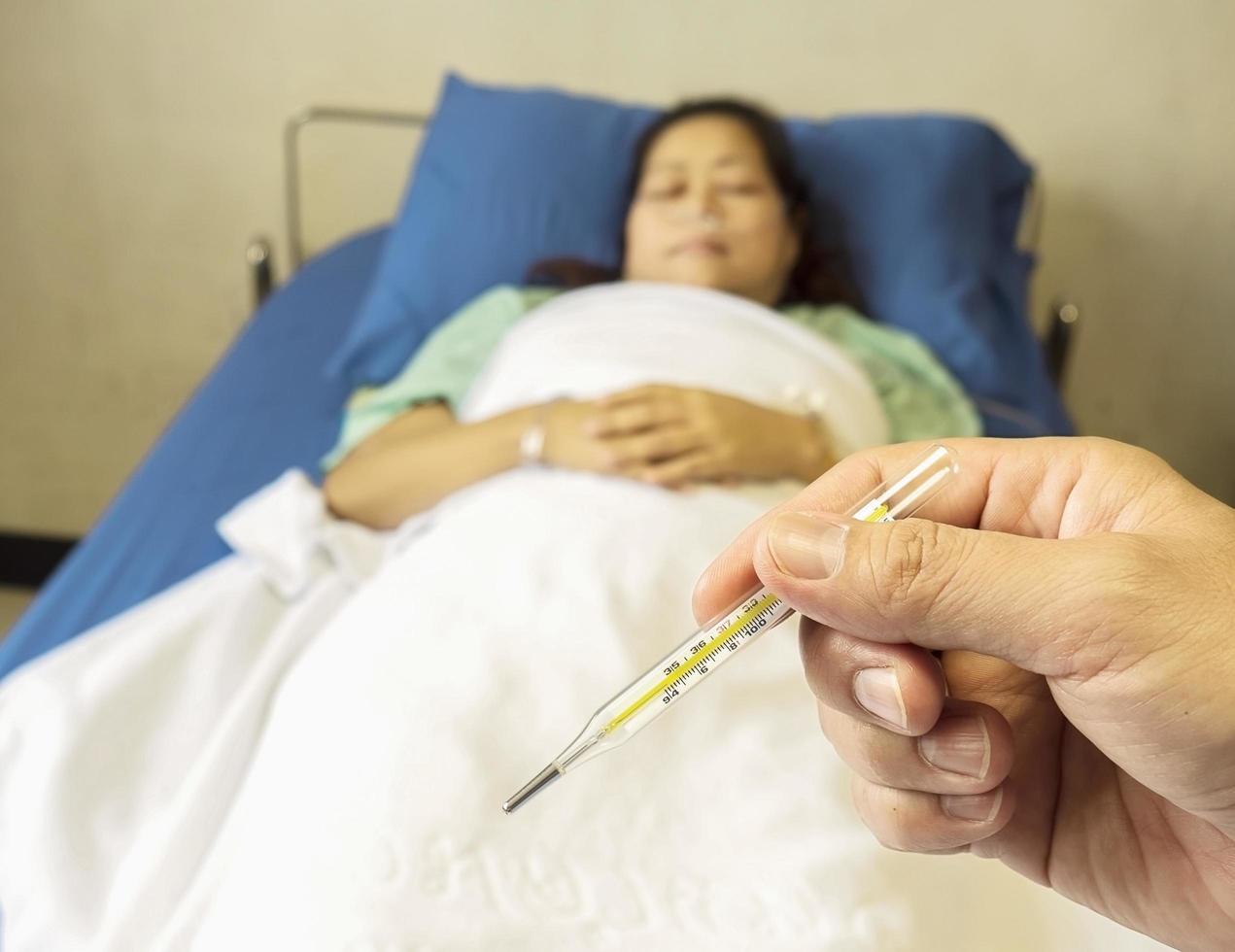A doctor is looking at thermometer for measuring body temperature of his patient. Photo is focused at thermometer.