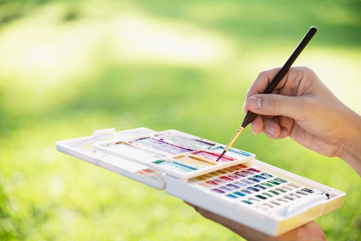 Relax woman painting water colour art work in green garden forest nature - people with creative art in nature stress reduction and meditation concept photo