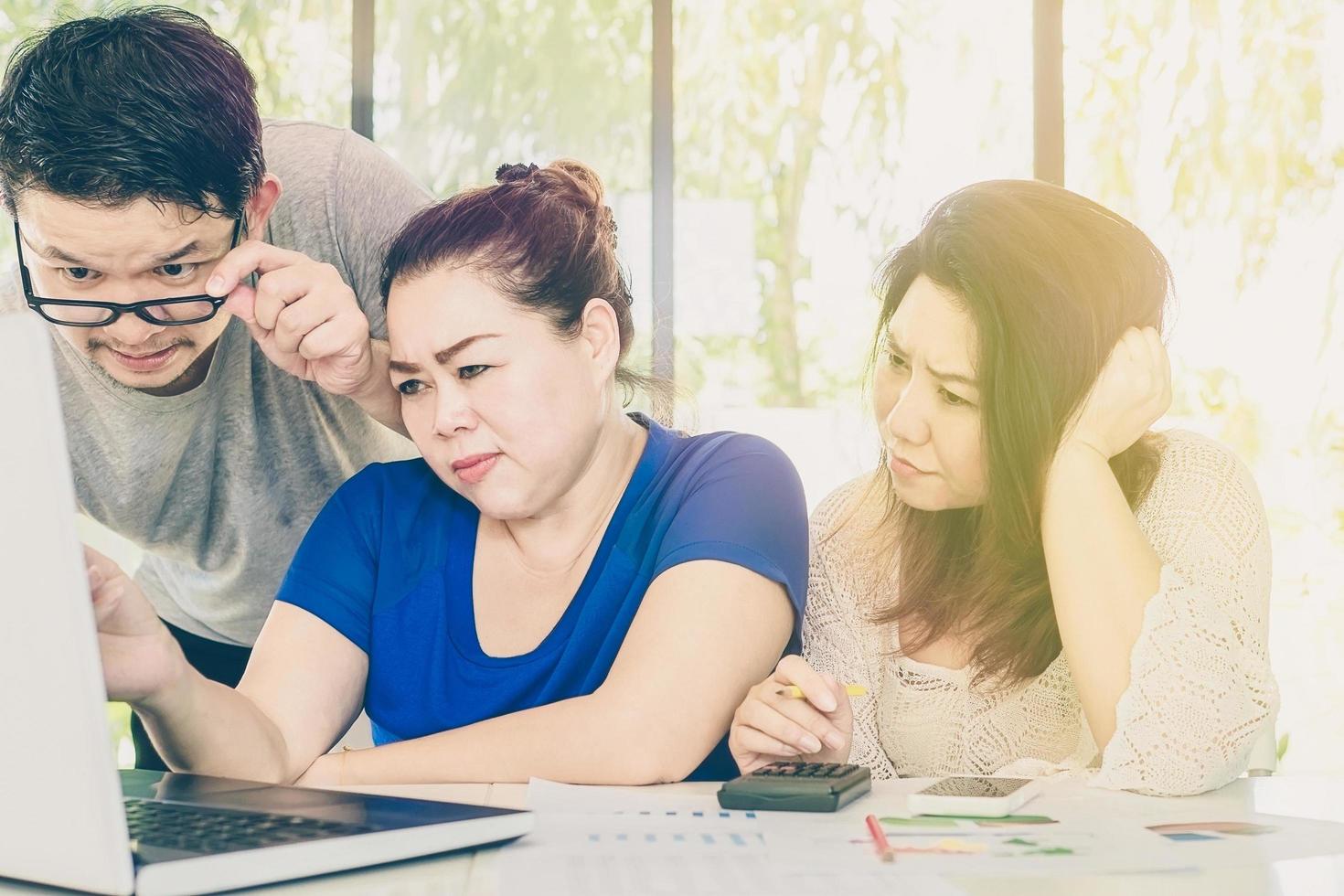 Vintage style photo of two women and one man is seriously working together in the modern office with warm light from top corner