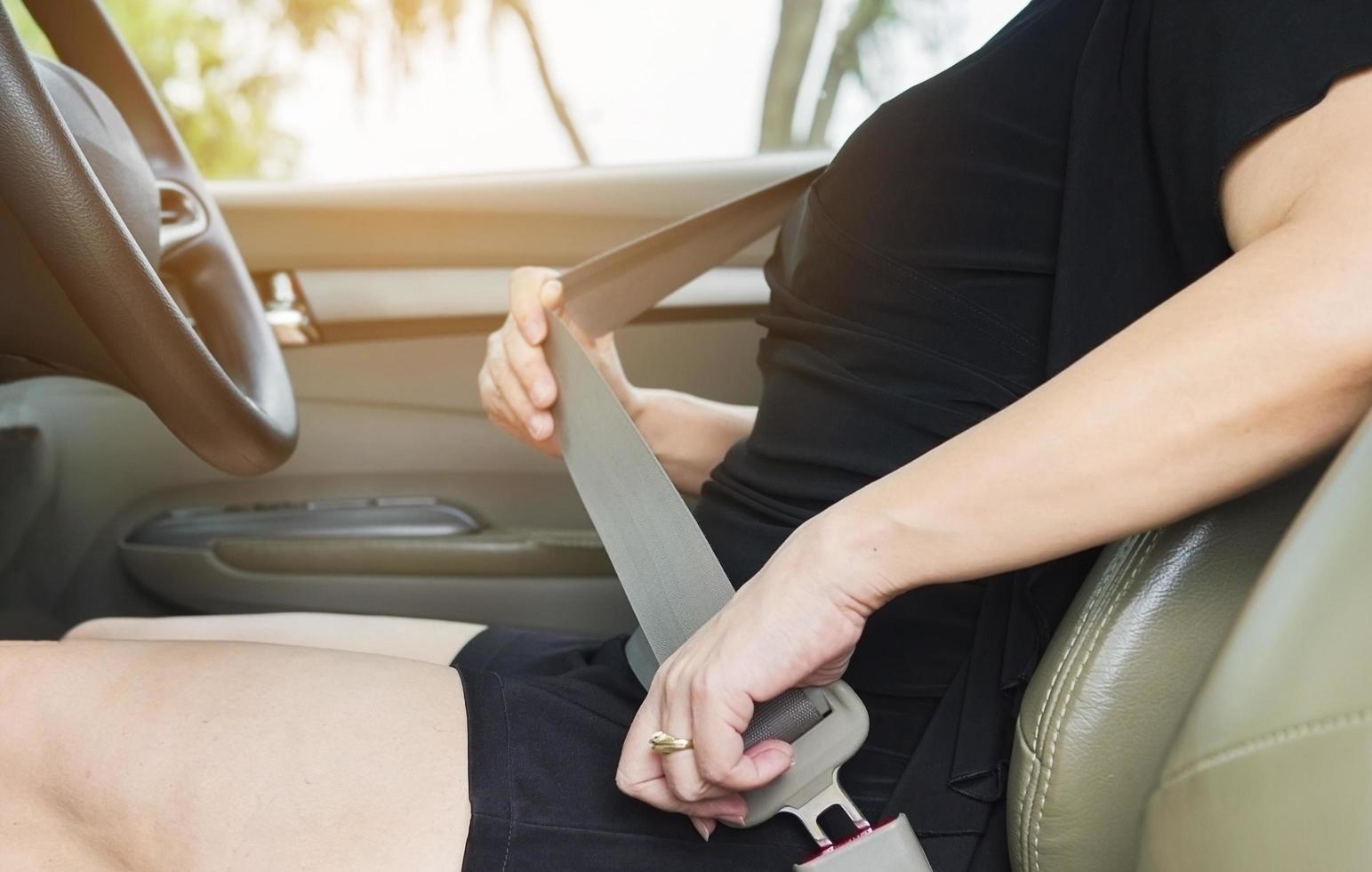 Lady putting car seat belt before driving, close up at belt buckle, safe drive concept photo