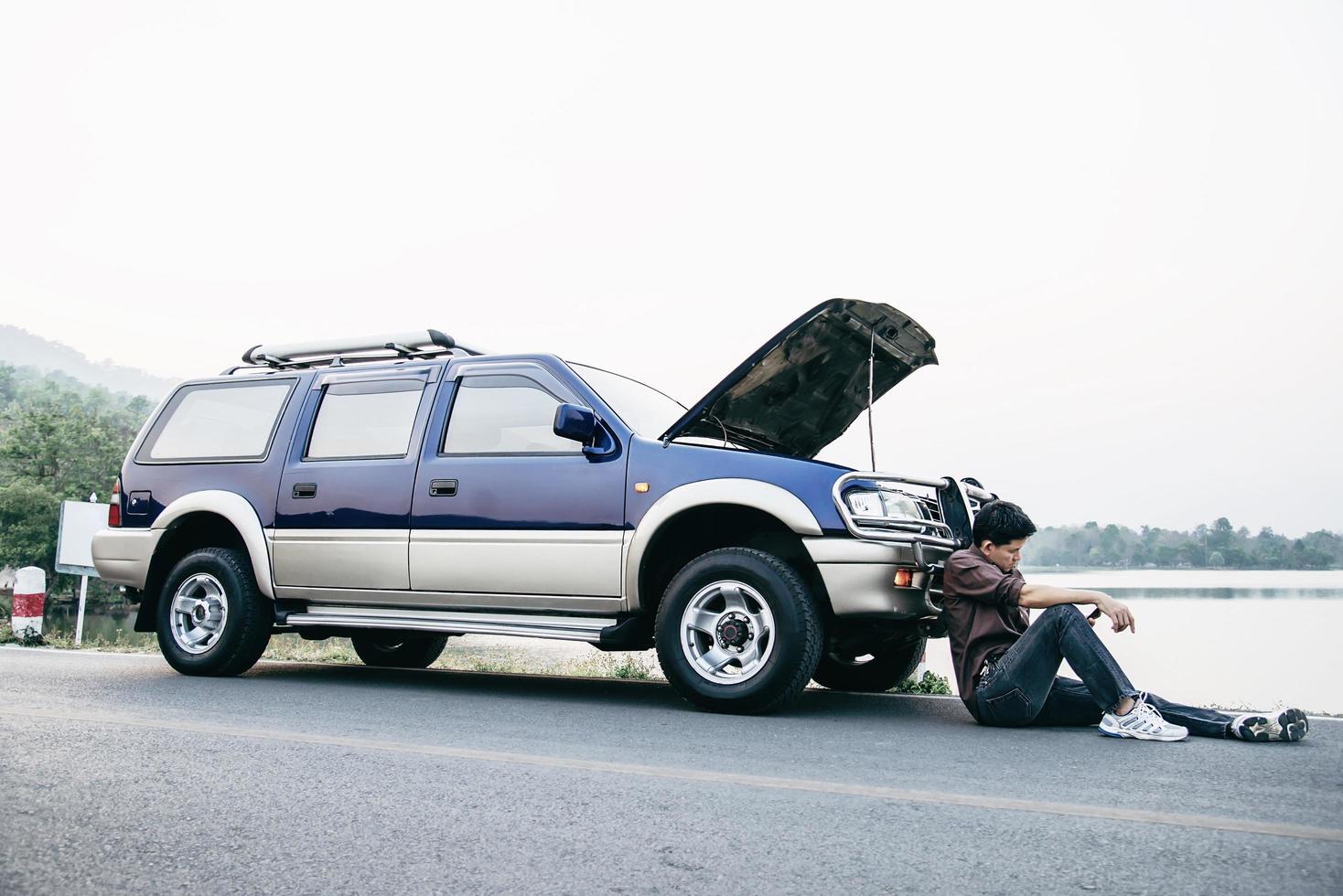 Man try to fix a car engine problem on a local road Chiang mai Thailand - people with car problem transportation concept photo