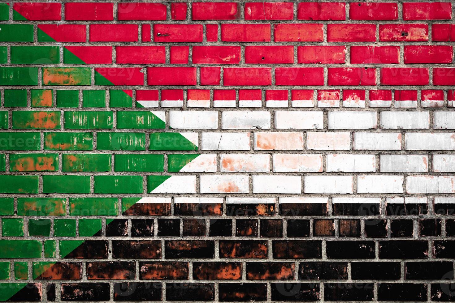 National  flag of the Sudan on a grunge brick background. photo