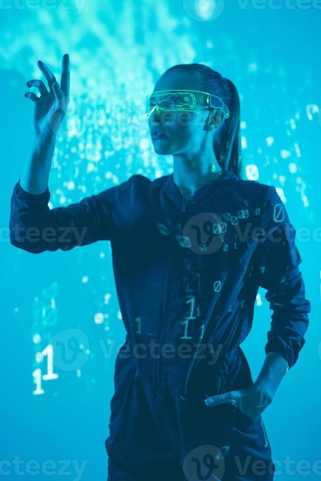 Confident young woman in futuristic glasses gesturing against colorful background photo