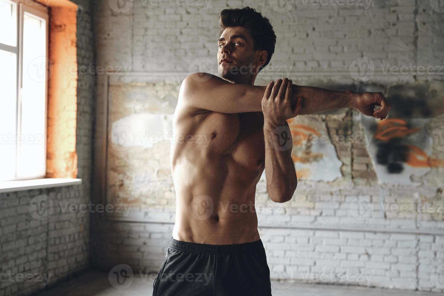 Handsome young man warming up before training in gym photo