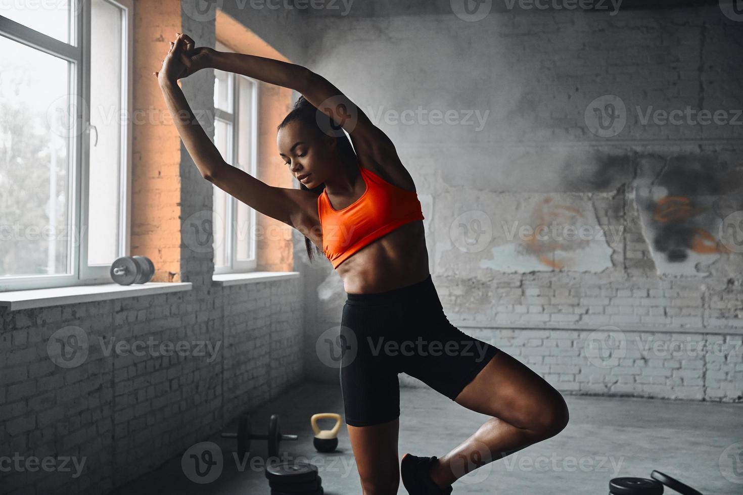 Beautiful young African woman in sports clothing exercising in gym photo