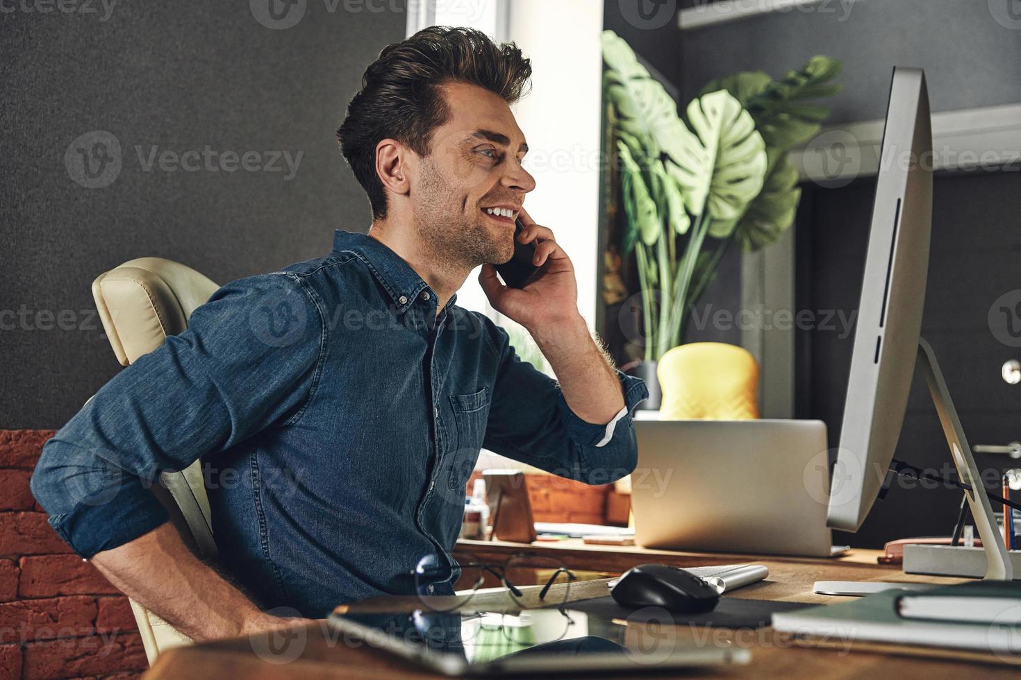 Young man sitting at desk in office and working on computer. Stock