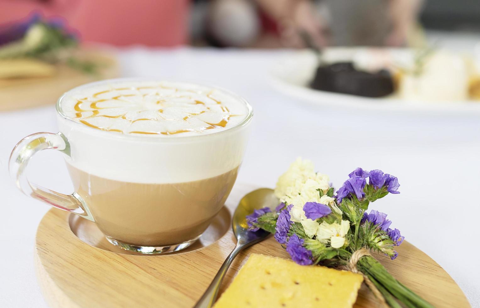 Well decorated hot coffee cup serve on wood dish and small violet flower and biscuits photo
